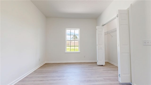 unfurnished bedroom featuring baseboards, a closet, and light wood finished floors
