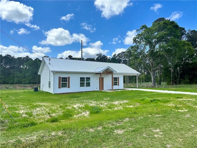 view of front of house featuring metal roof, a carport, and a front lawn