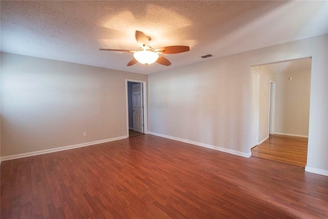 empty room featuring ceiling fan, a textured ceiling, and dark hardwood / wood-style flooring