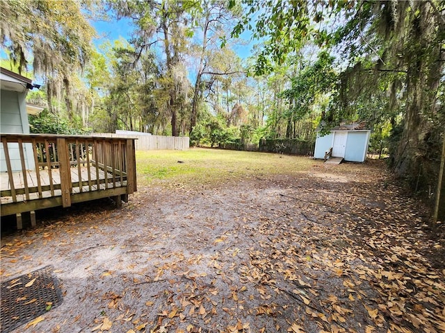 view of yard with a storage unit, a deck, an outdoor structure, and fence private yard