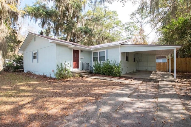 view of front of property featuring an attached carport, driveway, fence, and metal roof