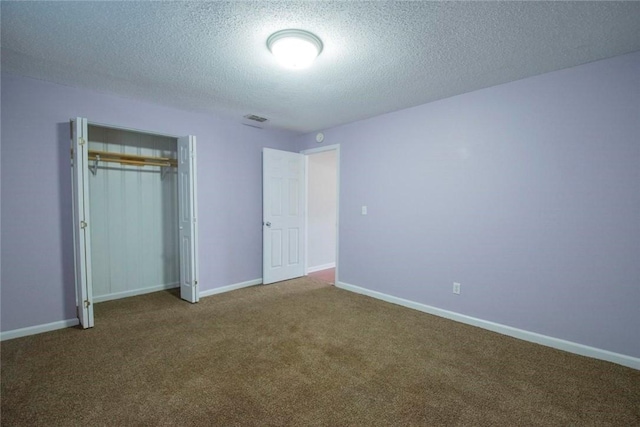 unfurnished bedroom with a textured ceiling, a closet, and carpet