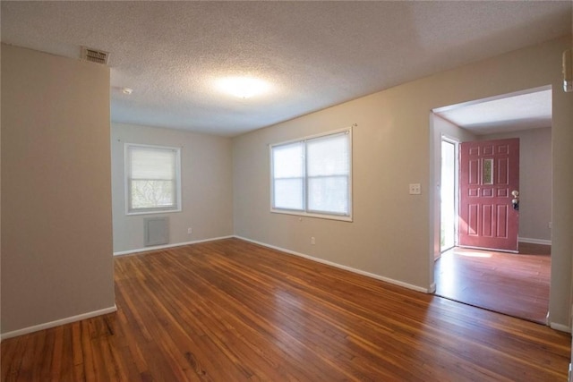 spare room with dark hardwood / wood-style floors and a textured ceiling