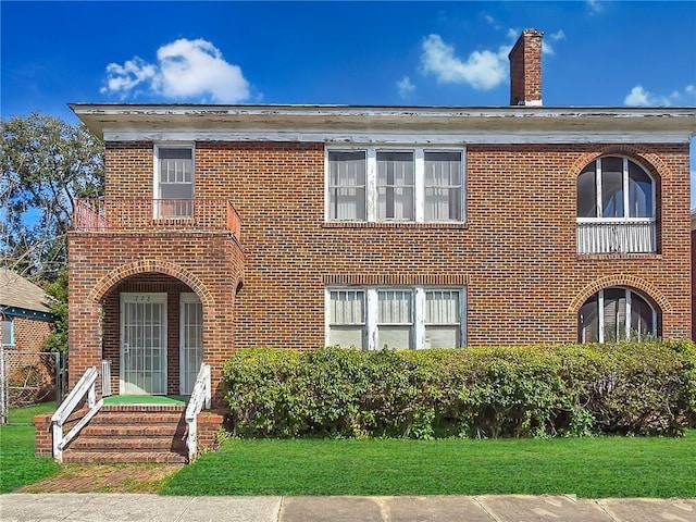 view of front of house featuring a front yard, brick siding, and a chimney