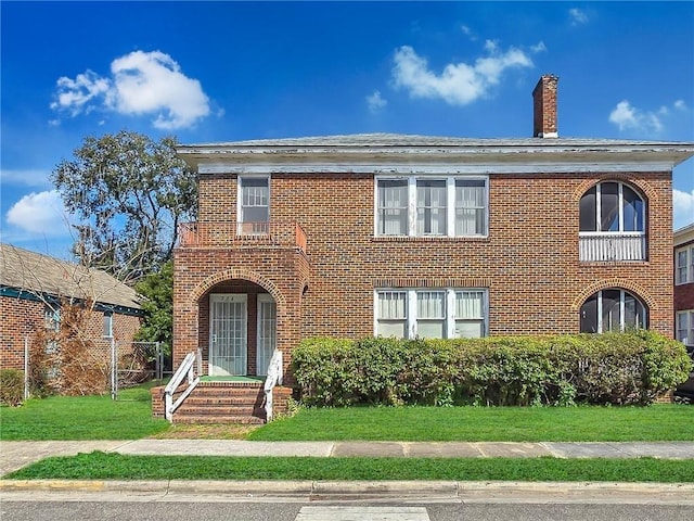 view of front of house with brick siding, a chimney, and a front yard