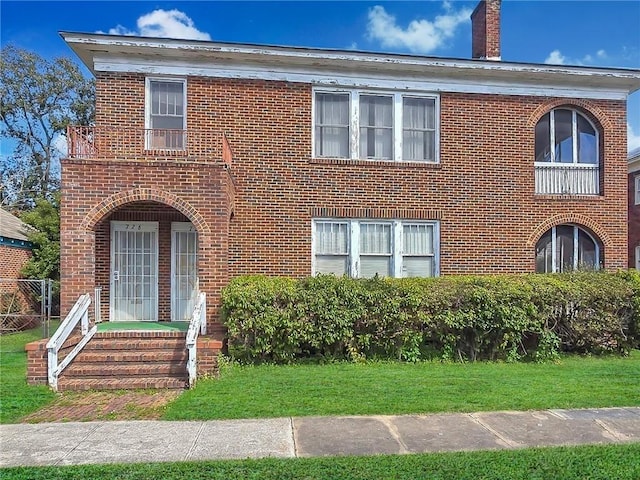 view of front of home featuring a front lawn, brick siding, and a chimney