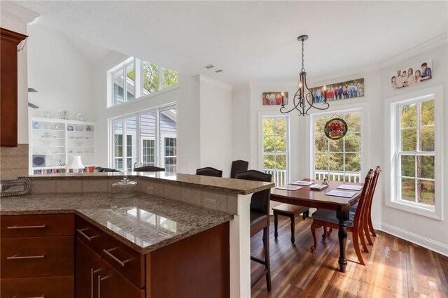 1068 Picnic Ln NE, Townsend, GA 31331 - interior space with wood finished floors, light stone countertops, hanging light fixtures, a breakfast bar area, and a notable chandelier