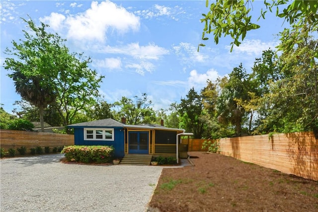view of outdoor structure with entry steps, a fenced backyard, and gravel driveway
