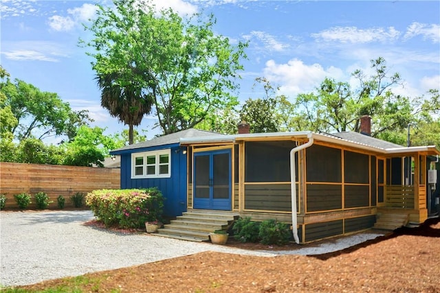 view of front of home featuring fence, entry steps, board and batten siding, and a chimney