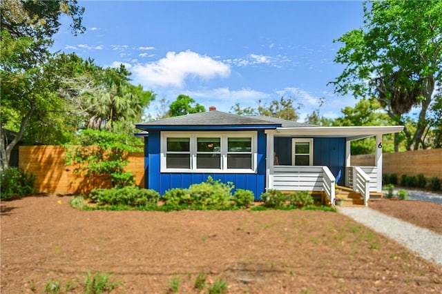 bungalow-style house featuring board and batten siding, covered porch, and fence