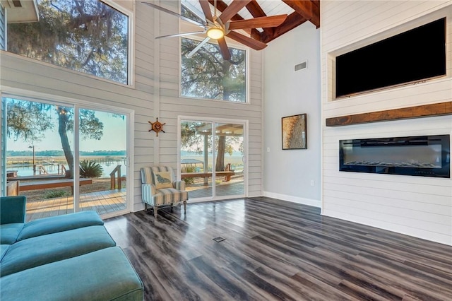 living room featuring dark wood-type flooring, plenty of natural light, and a towering ceiling