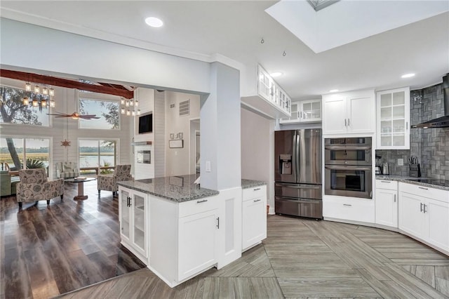 kitchen with backsplash, stainless steel appliances, dark stone counters, and white cabinets