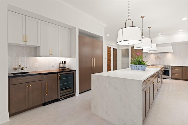 50 Frederica Oaks Ln, Saint Simons Island, GA 31522 - kitchen featuring wine cooler, backsplash, a center island, custom range hood, and hanging light fixtures