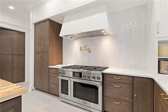 50 Frederica Oaks Ln, Saint Simons Island, GA 31522 - kitchen with double oven range, premium range hood, light countertops, backsplash, and dark brown cabinetry