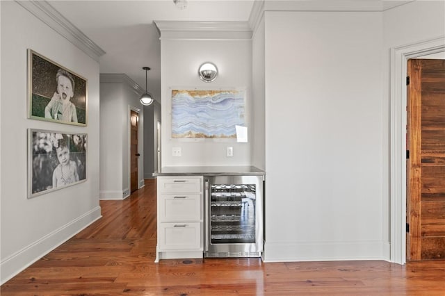 50 Frederica Oaks Ln, Saint Simons Island, GA 31522 - indoor dry bar with wine cooler, crown molding, dark wood-style flooring, baseboards, and hanging light fixtures