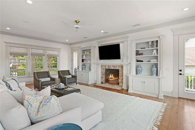 50 Frederica Oaks Ln, Saint Simons Island, GA 31522 - living room featuring plenty of natural light, light wood-type flooring, ceiling fan, a fireplace, and ornamental molding