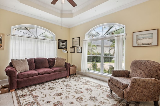 tiled living room featuring a raised ceiling, ceiling fan, and crown molding