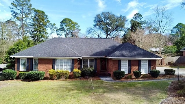 ranch-style house featuring brick siding, roof with shingles, fence, and a front yard