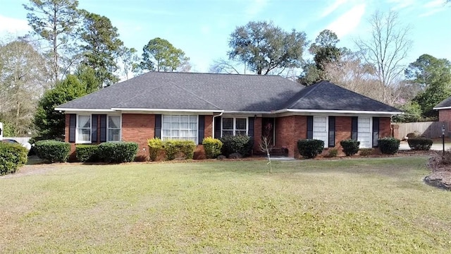 single story home with brick siding, fence, a front lawn, and roof with shingles