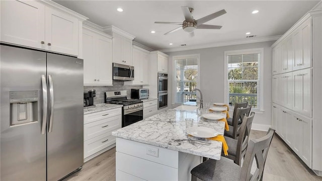 kitchen featuring visible vents, decorative backsplash, appliances with stainless steel finishes, ornamental molding, and a sink