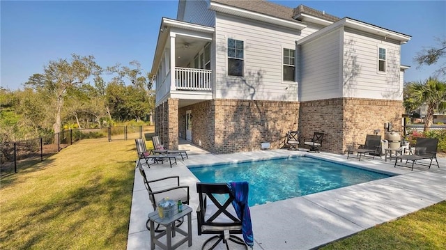 rear view of house featuring a patio, a balcony, brick siding, fence, and a yard