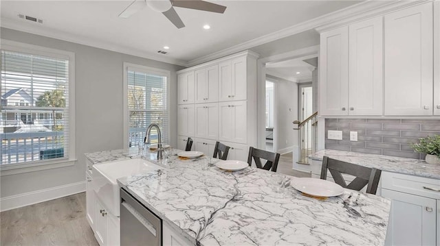 kitchen with crown molding, visible vents, backsplash, stainless steel dishwasher, and a sink