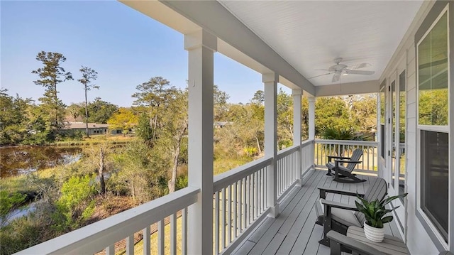 wooden deck with a water view and ceiling fan