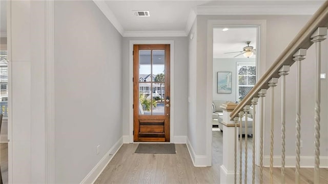 entryway with baseboards, visible vents, light wood-style flooring, stairs, and crown molding