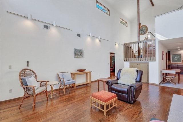 living room with a towering ceiling and hardwood / wood-style flooring