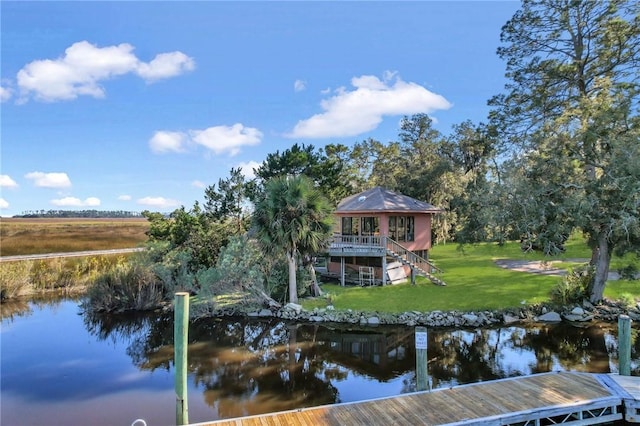 view of dock with a lawn and a water view