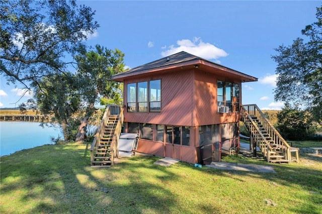 rear view of property featuring a sunroom, a water view, and a lawn