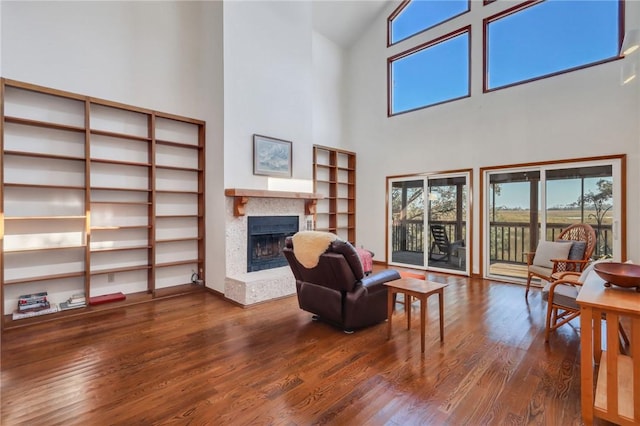 sitting room with hardwood / wood-style floors and high vaulted ceiling