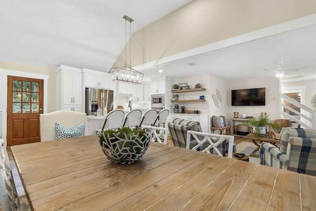 dining space with ceiling fan, lofted ceiling, and sink