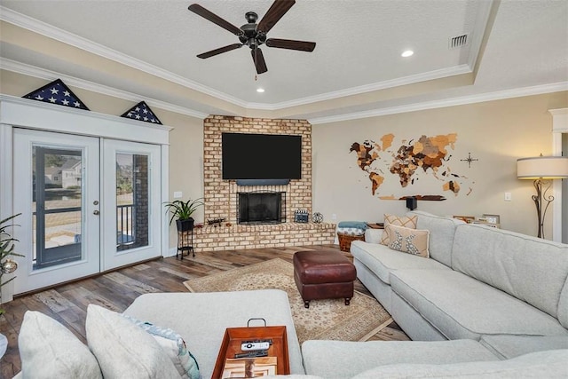 living room featuring a fireplace, wood-type flooring, ceiling fan, and ornamental molding