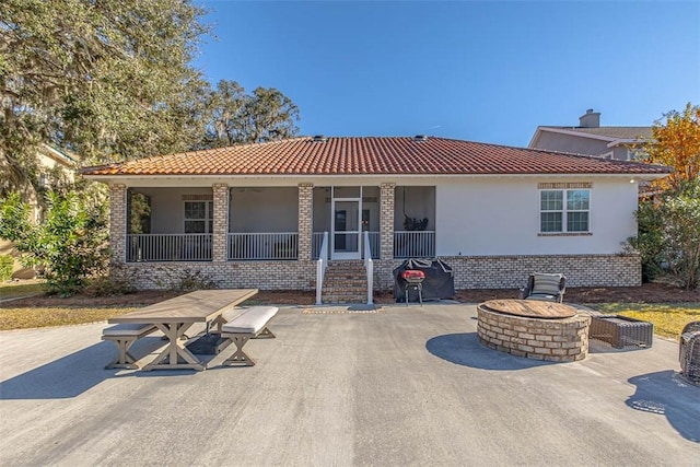 rear view of property with an outdoor fire pit and a patio