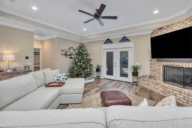 living room with ceiling fan, light wood-type flooring, crown molding, and french doors