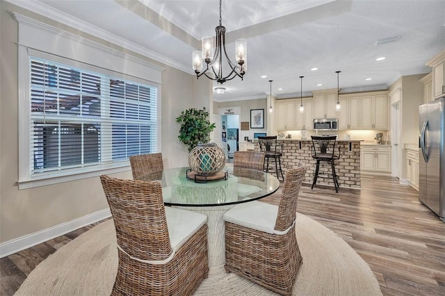 dining area featuring an inviting chandelier, ornamental molding, and light hardwood / wood-style flooring