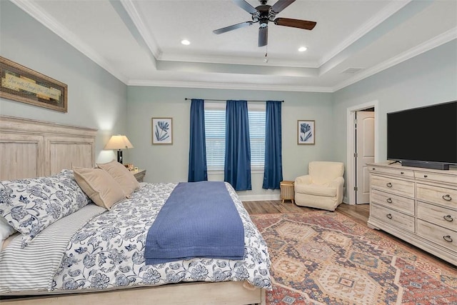 bedroom featuring hardwood / wood-style floors, a raised ceiling, ceiling fan, and crown molding