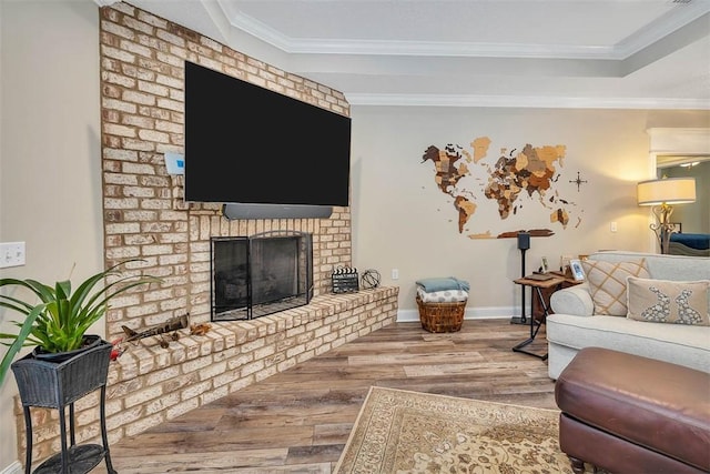 living room featuring hardwood / wood-style flooring, a brick fireplace, and ornamental molding