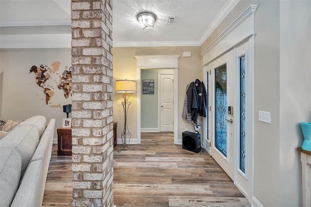 foyer entrance featuring hardwood / wood-style flooring, ornamental molding, a textured ceiling, and french doors