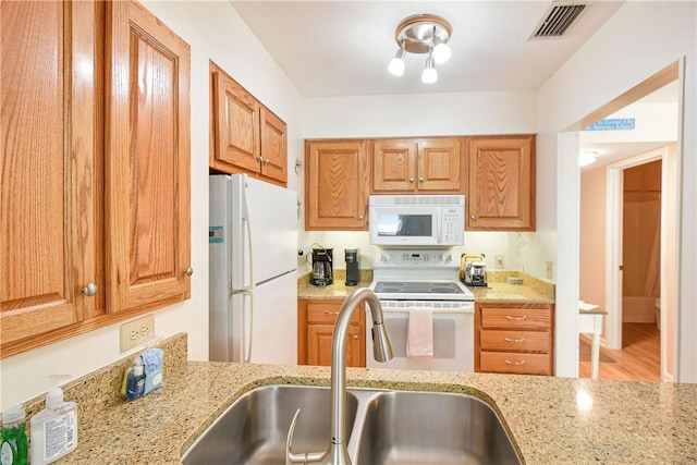 1524 Wood Ave Unit 314, Saint Simons Island, GA 31522 - kitchen featuring white appliances, a sink, light stone countertops, brown cabinets, and light wood-style flooring