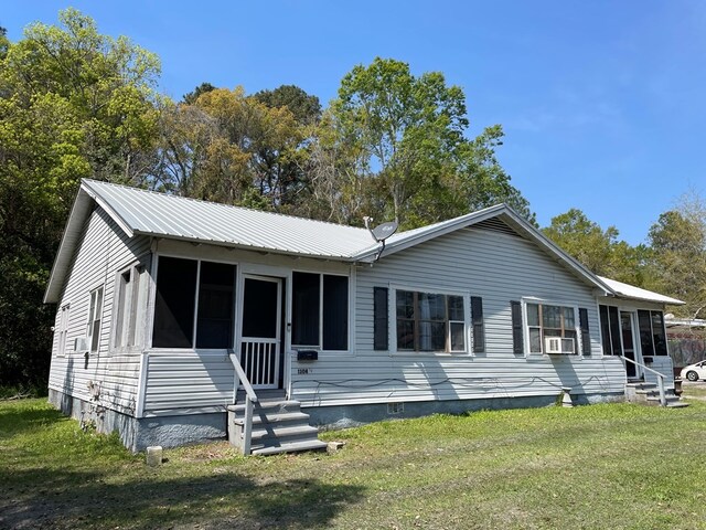 view of front of property featuring a sunroom, cooling unit, and a front yard