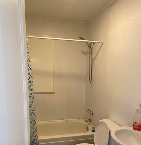 bathroom with shower / tub combo with curtain and toilet