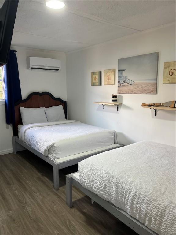 bedroom featuring a wall unit AC and dark hardwood / wood-style floors