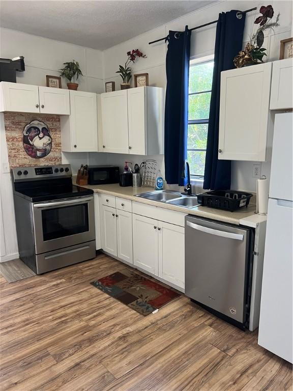 kitchen featuring white cabinets, stainless steel appliances, and wood-type flooring