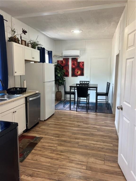 kitchen with white cabinetry, sink, dishwasher, and hardwood / wood-style flooring