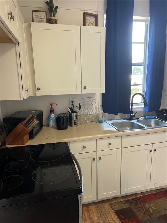 kitchen featuring sink, white cabinets, hardwood / wood-style floors, and black electric range