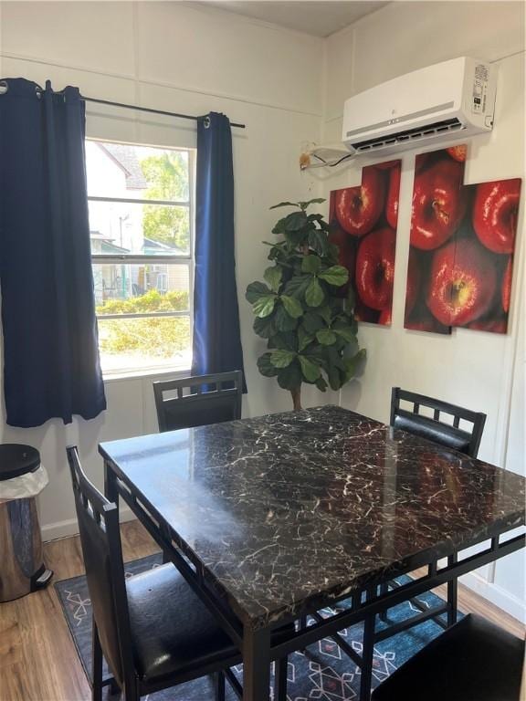 dining space featuring an AC wall unit and hardwood / wood-style flooring