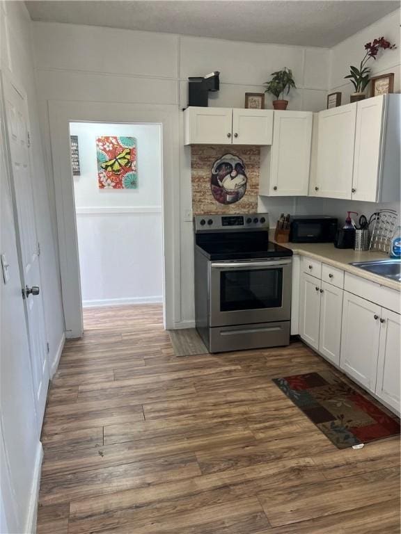 kitchen featuring sink, white cabinets, stainless steel range with electric stovetop, and hardwood / wood-style flooring