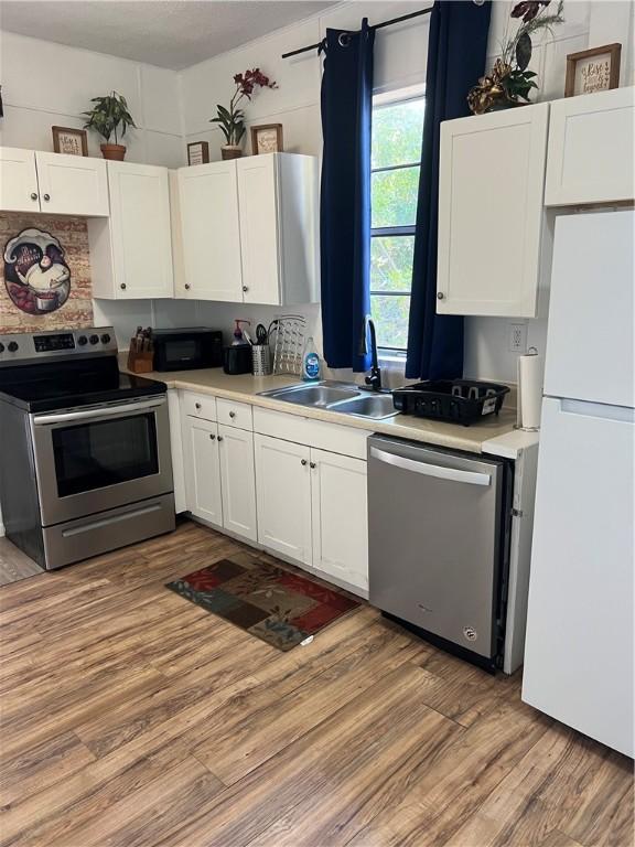 kitchen featuring white cabinetry, sink, stainless steel appliances, and light wood-type flooring